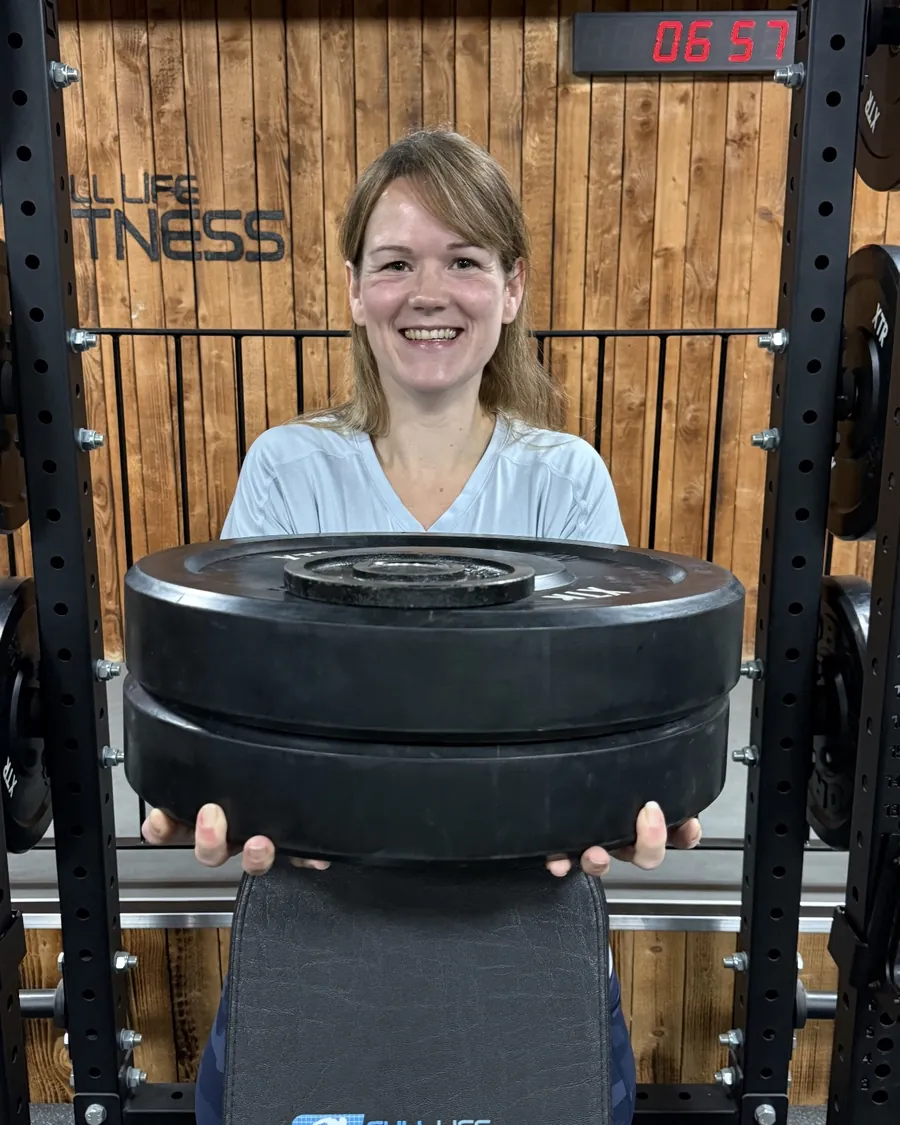 A member carrying weight plates across the training room